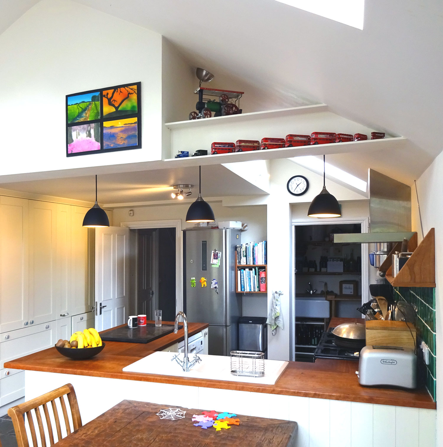 interior view of kitchen peninsula with sink and three pendant ligths above, exposed painted steel beam above 